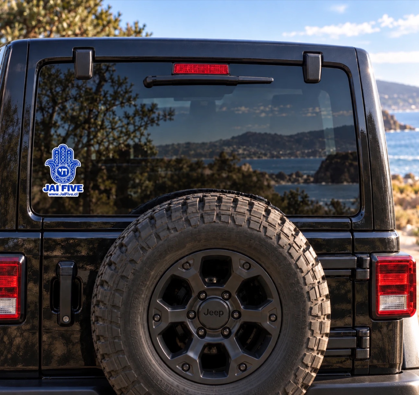 Jai Five sticker on the rear window of a black jeep, with the ocean behind it